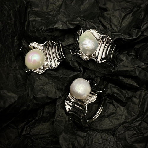 Pearl earrings with silver settings on a black crumpled fabric background